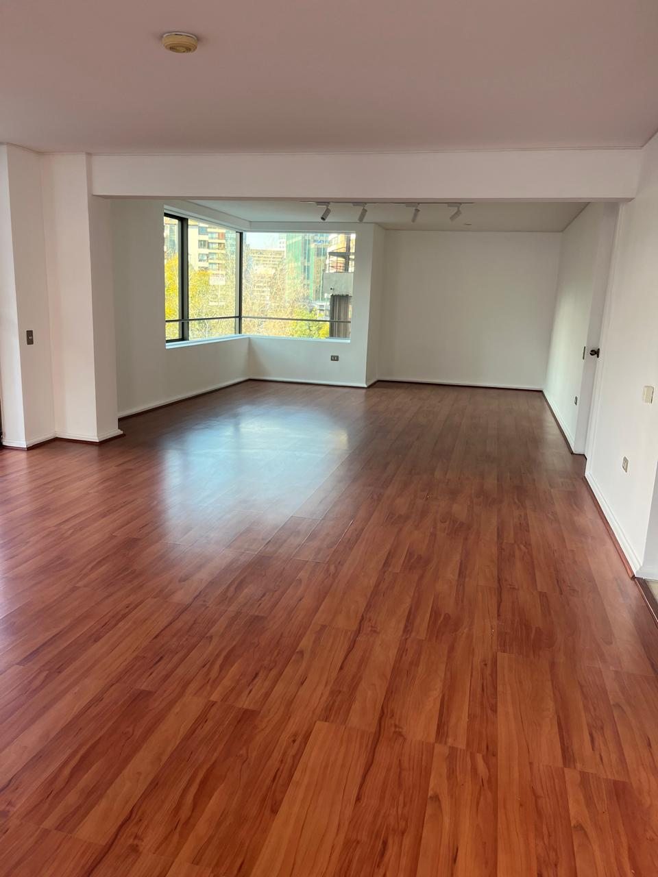 Recinto con piso de madera y ventanal de esquina tras la remodelación, Isidora Goyenechea