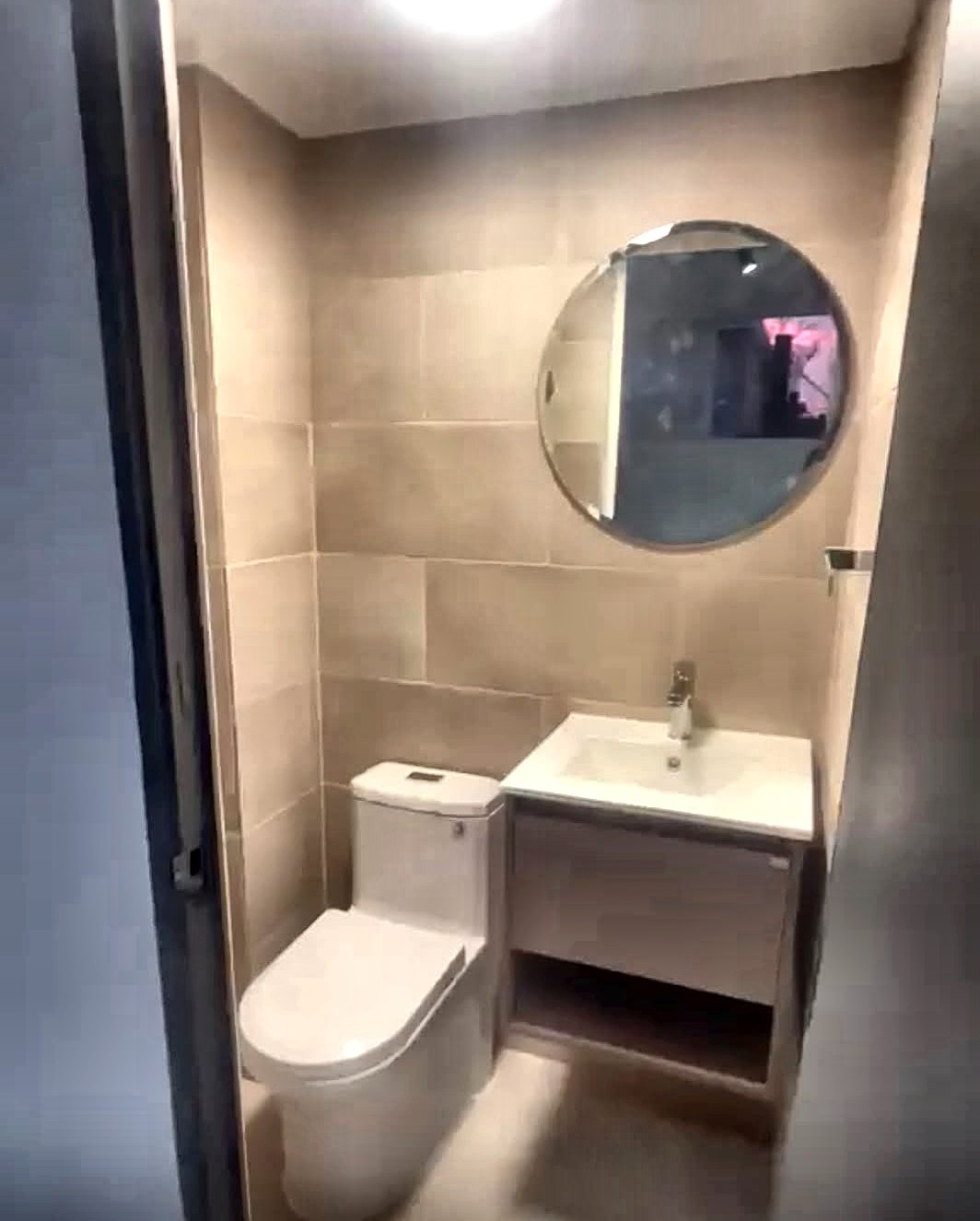 Baño con revestimiento cerámico, mueble vanitorio y espejo circular, Apoquindo