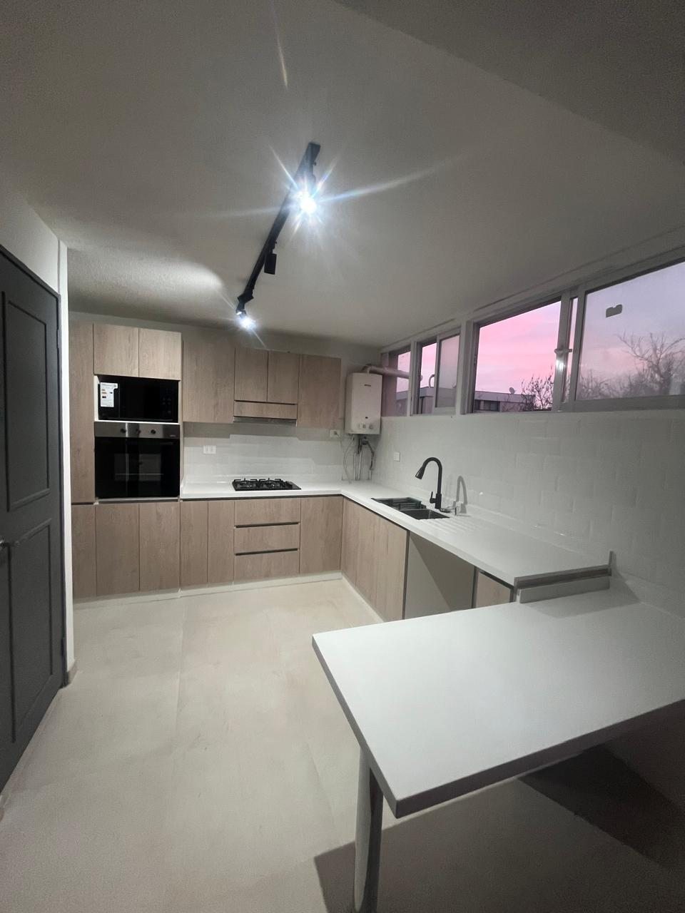 Cocina remodelada con muebles a medida, encimera de cuarzo y mesón de apoyo, Apoquindo