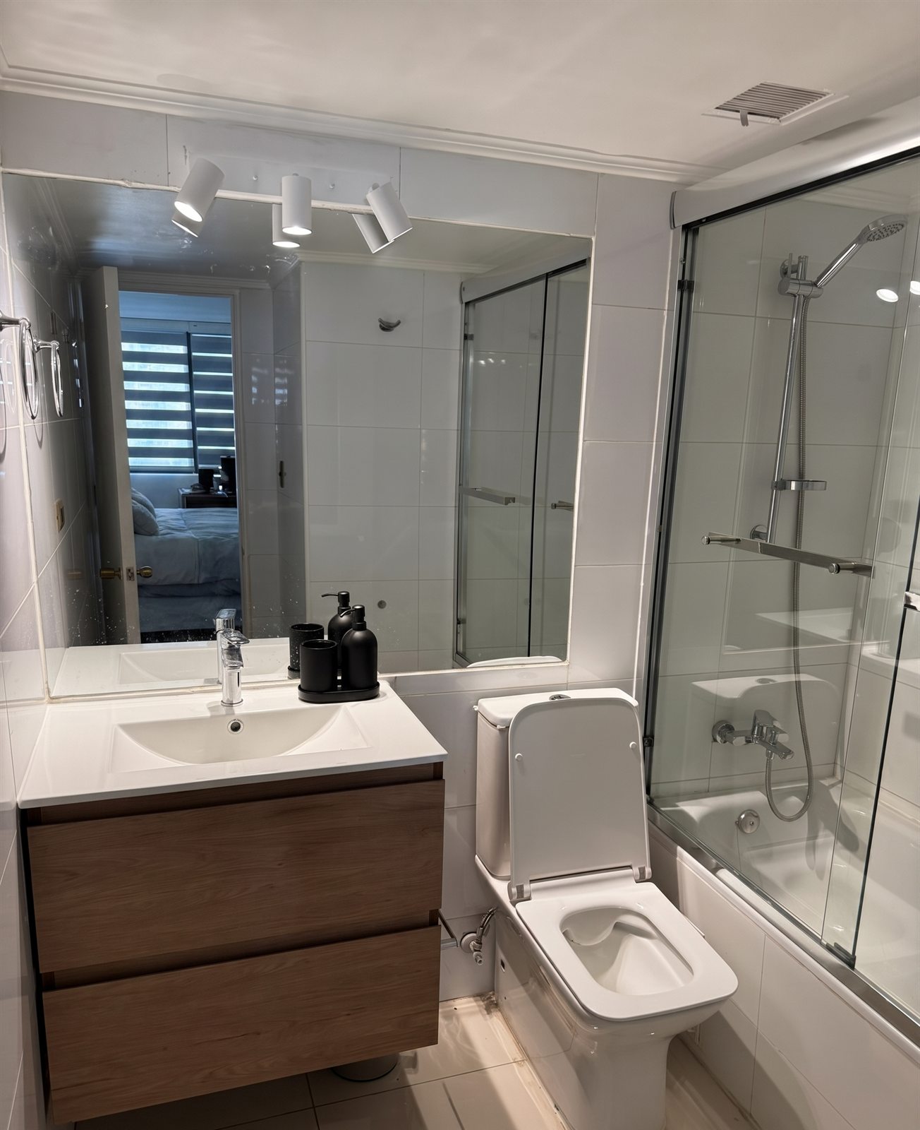 Baño remodelado con mueble de madera, artefactos nuevos y tina con mampara, San Sebastián